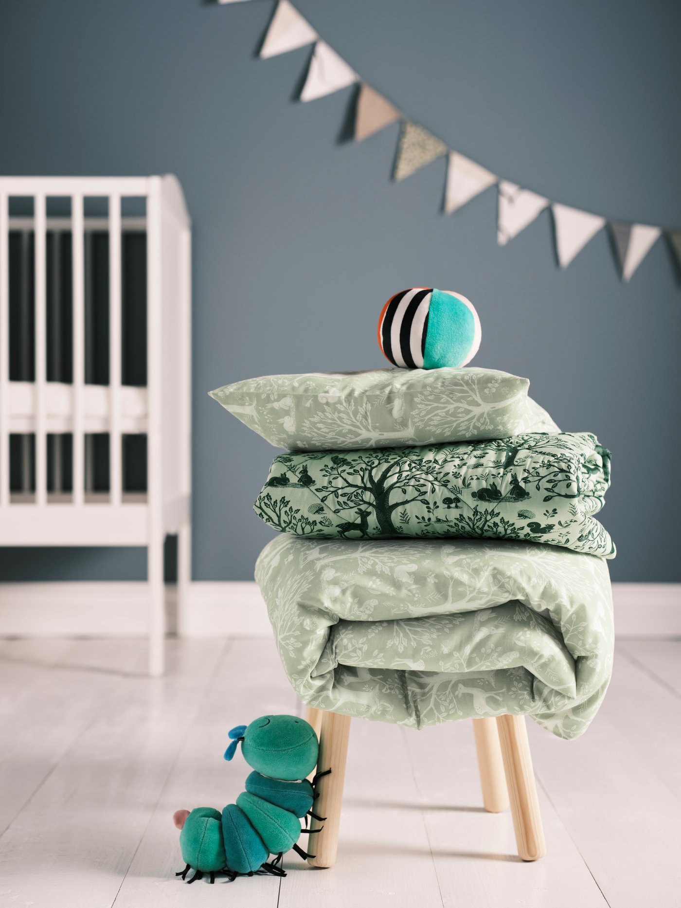 Green TROLLDOM duvet cover and pillowcase for crib with patterns of forest animals and nature details.
