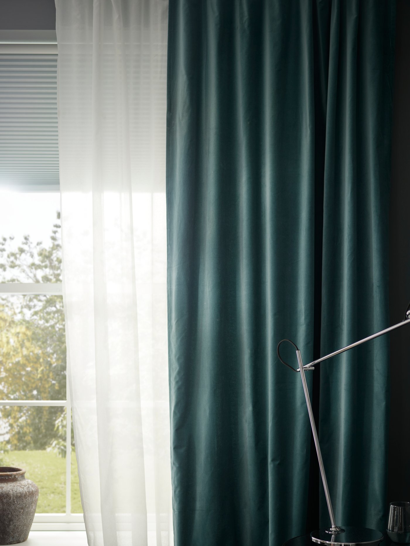 Close-up of window with blinds, sheer white curtains and dark turquoise SANELA curtains in room darkening cotton velvet.