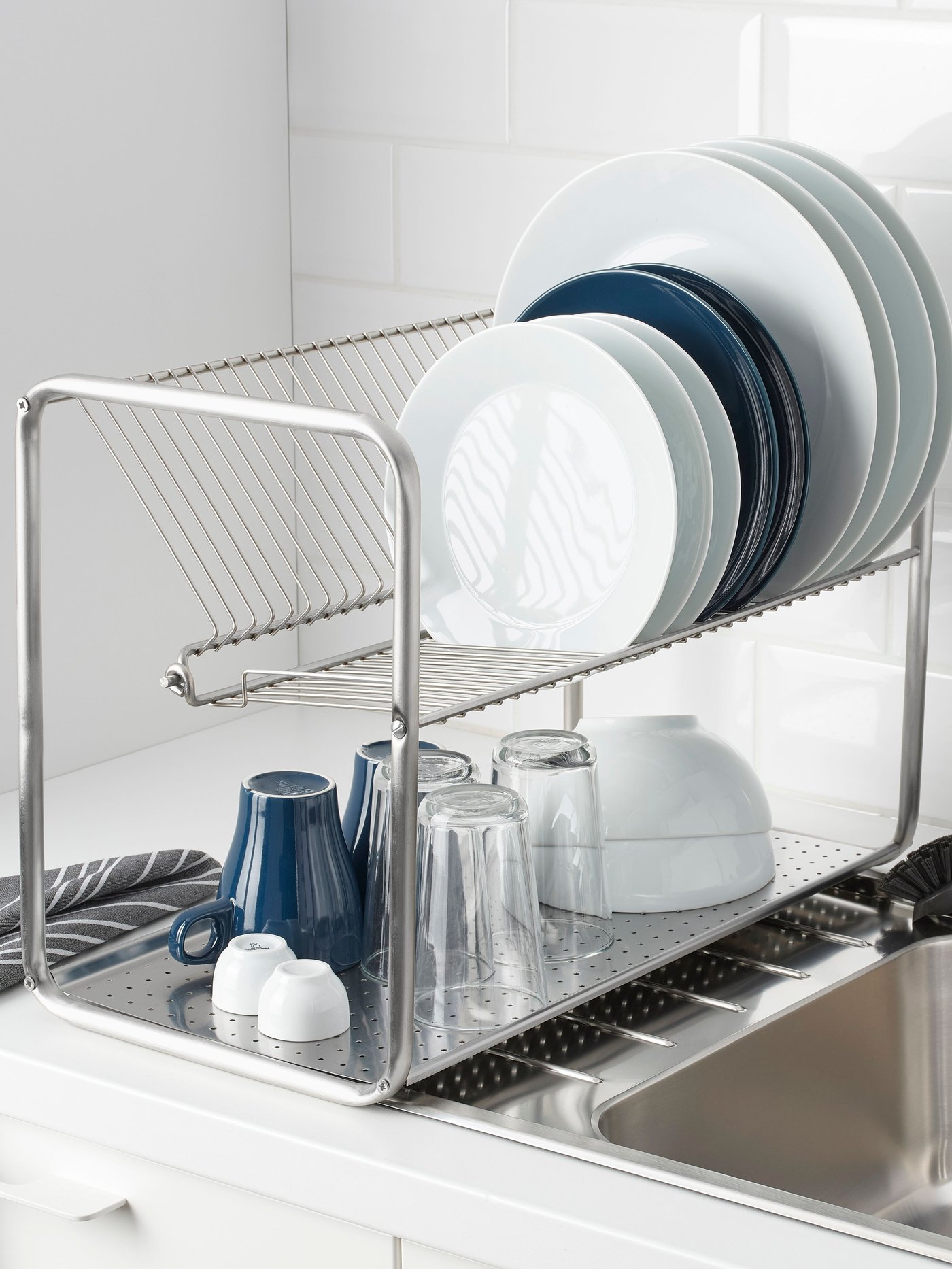Un secador de platos ORDNING con vajilla blanca y celeste sobre un lavaplatos IKEA.