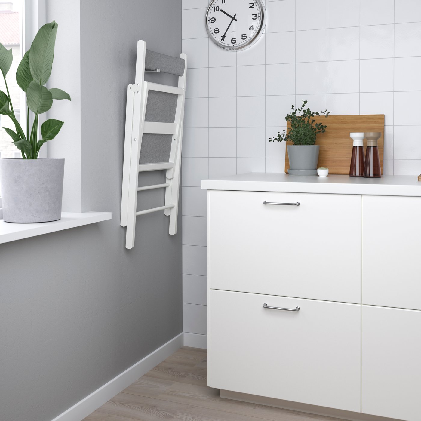 Una silla plegable FRÖSVI blanca/gris claro Knisa en la cocina.
