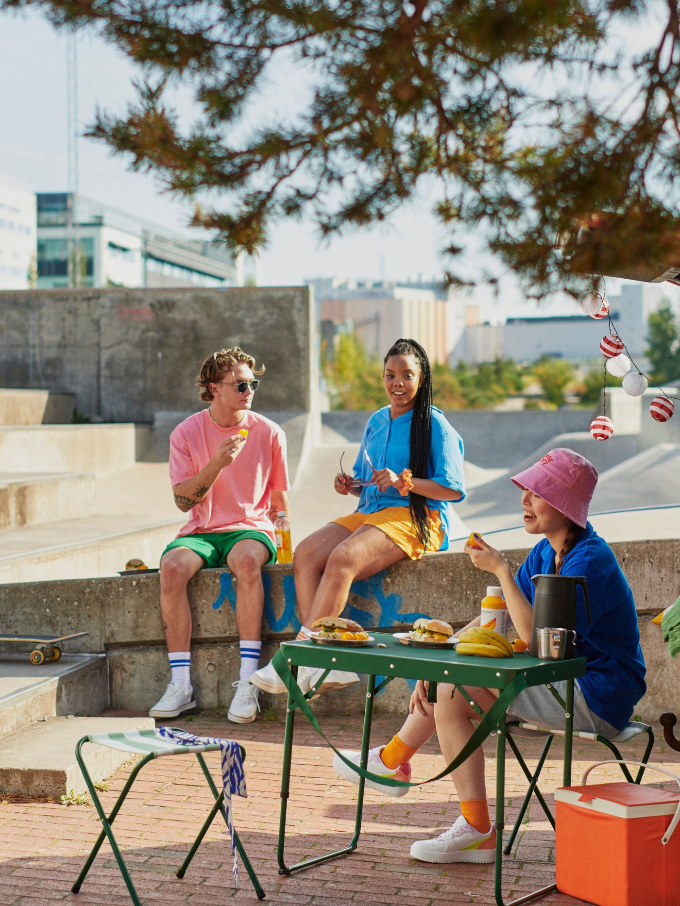 Tres personas en un espacio al aire libre rural una de ellas sentada en un piso STRANDÖN.