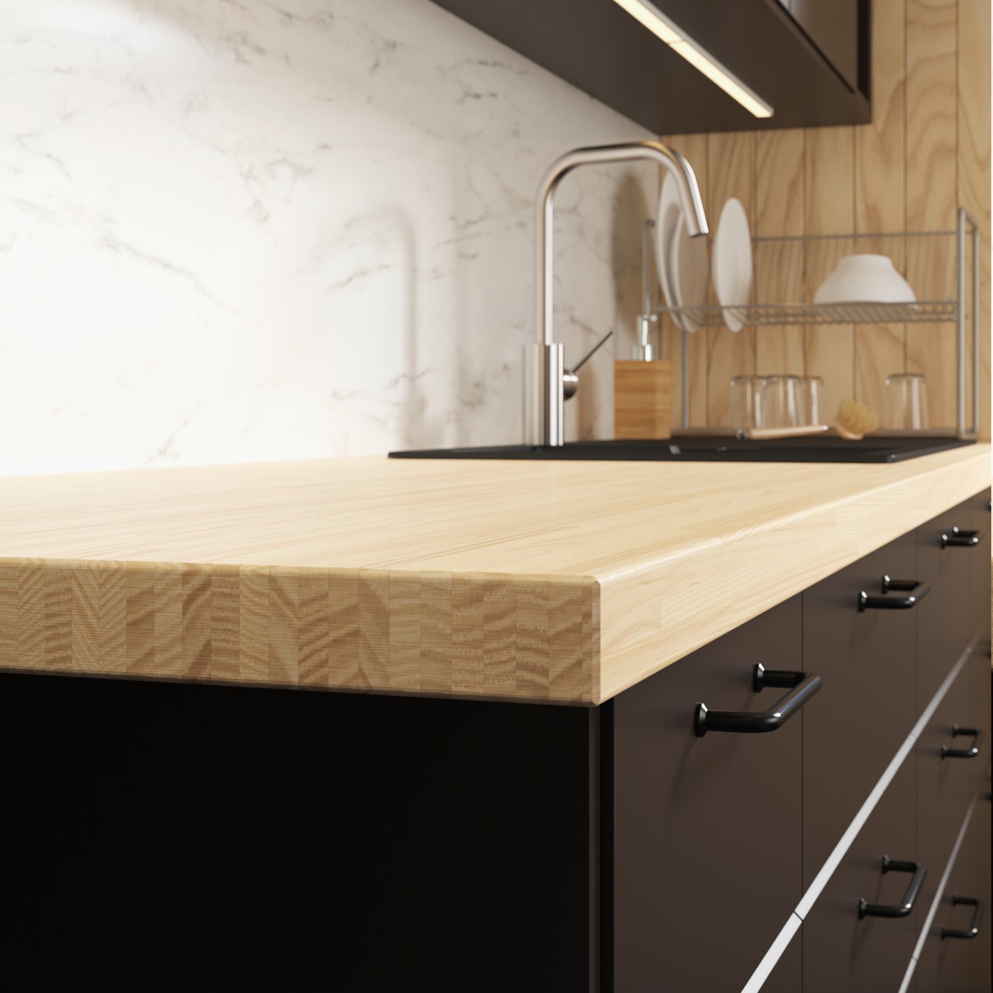 cubierta de cocina en tonos café claro y negro. Se ve un lavaplatos y platos secando.