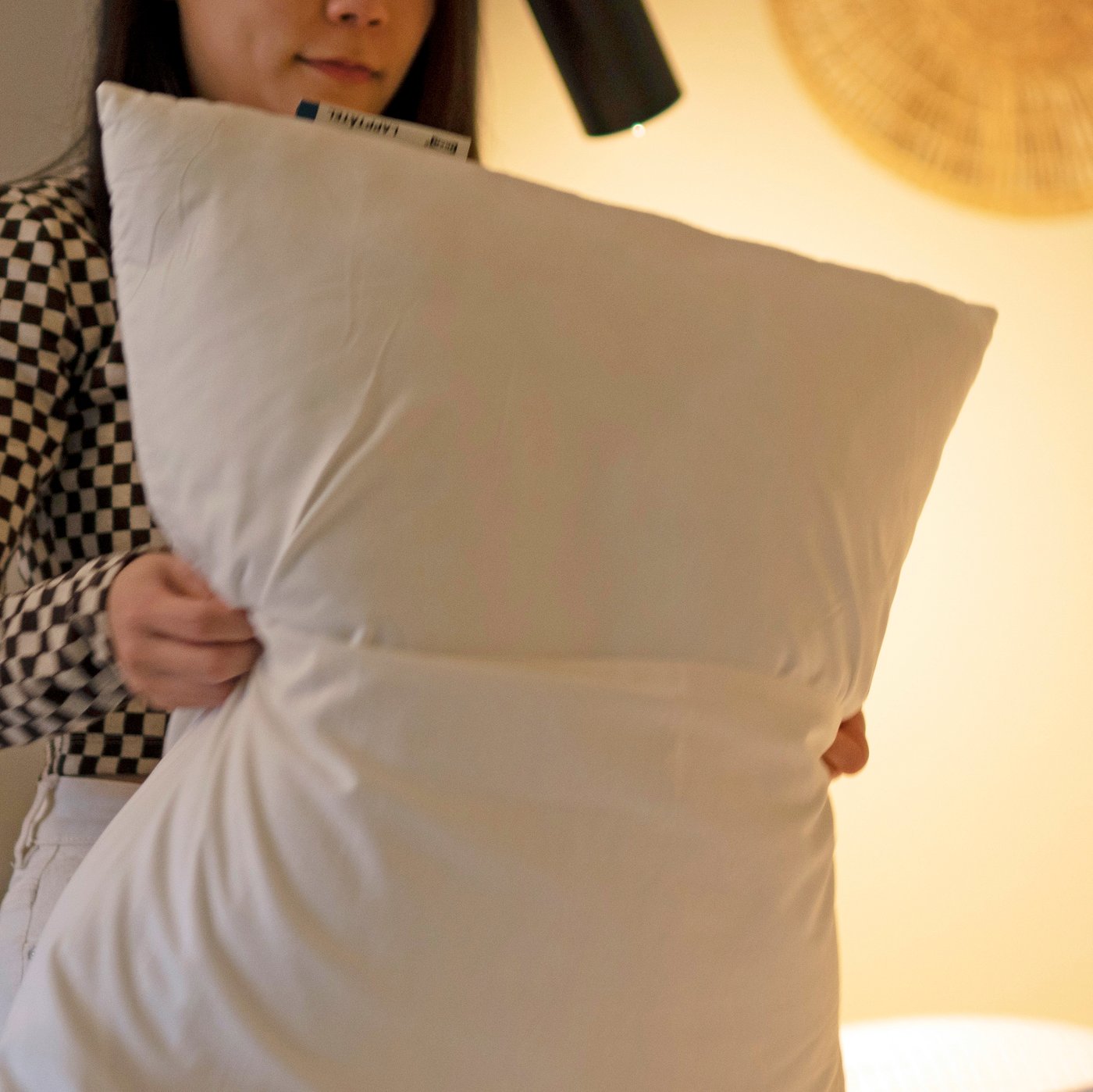 Una mujer prepara una almohada LAPPTÅTEL con una funda para almohada DVALA para una sesión de estiramientos en la cama.