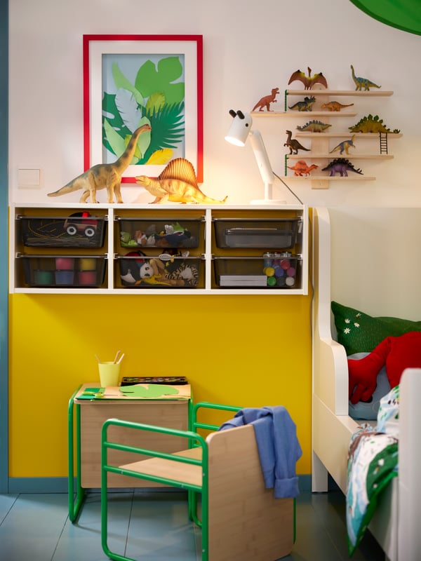 A children’s room with wall mounted TROFAST storage combination with boxes and SMÅSKRAKE multi-functional child chair/table.