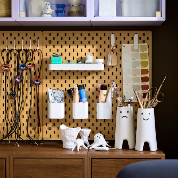 Close-up of a wall pegboard with an attached white SKÅDIS 7-piece accessories set, neatly arranged for crafting supplies.