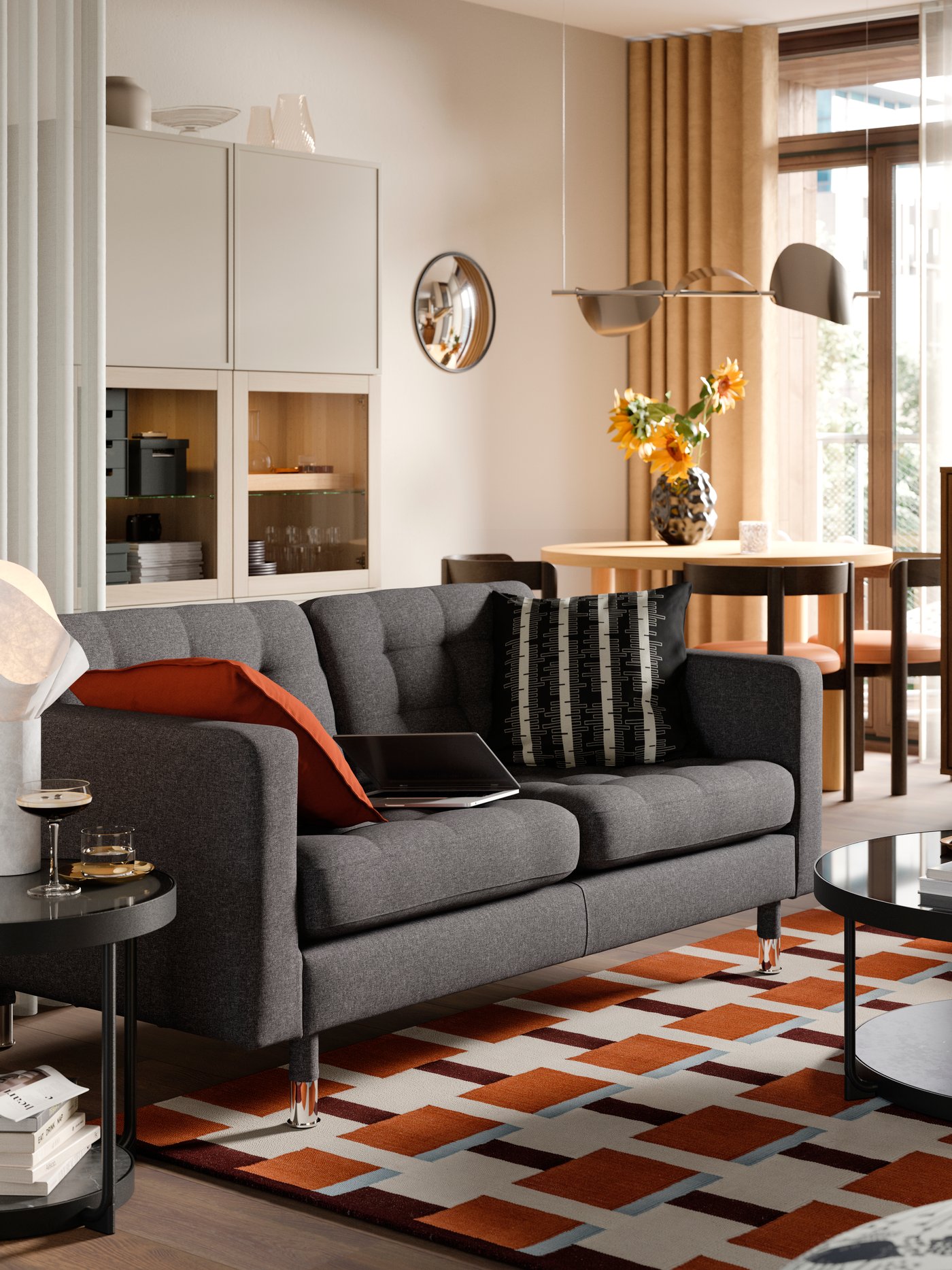 A dark grey 2-seat sofa stands in a living room near some BESTÅ storage and a RÅDMANSJÖ cabinet.