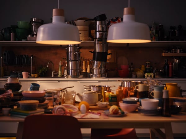 une table à manger remplie de vaisselles, bols, et casseroles empilés les uns sur les autres