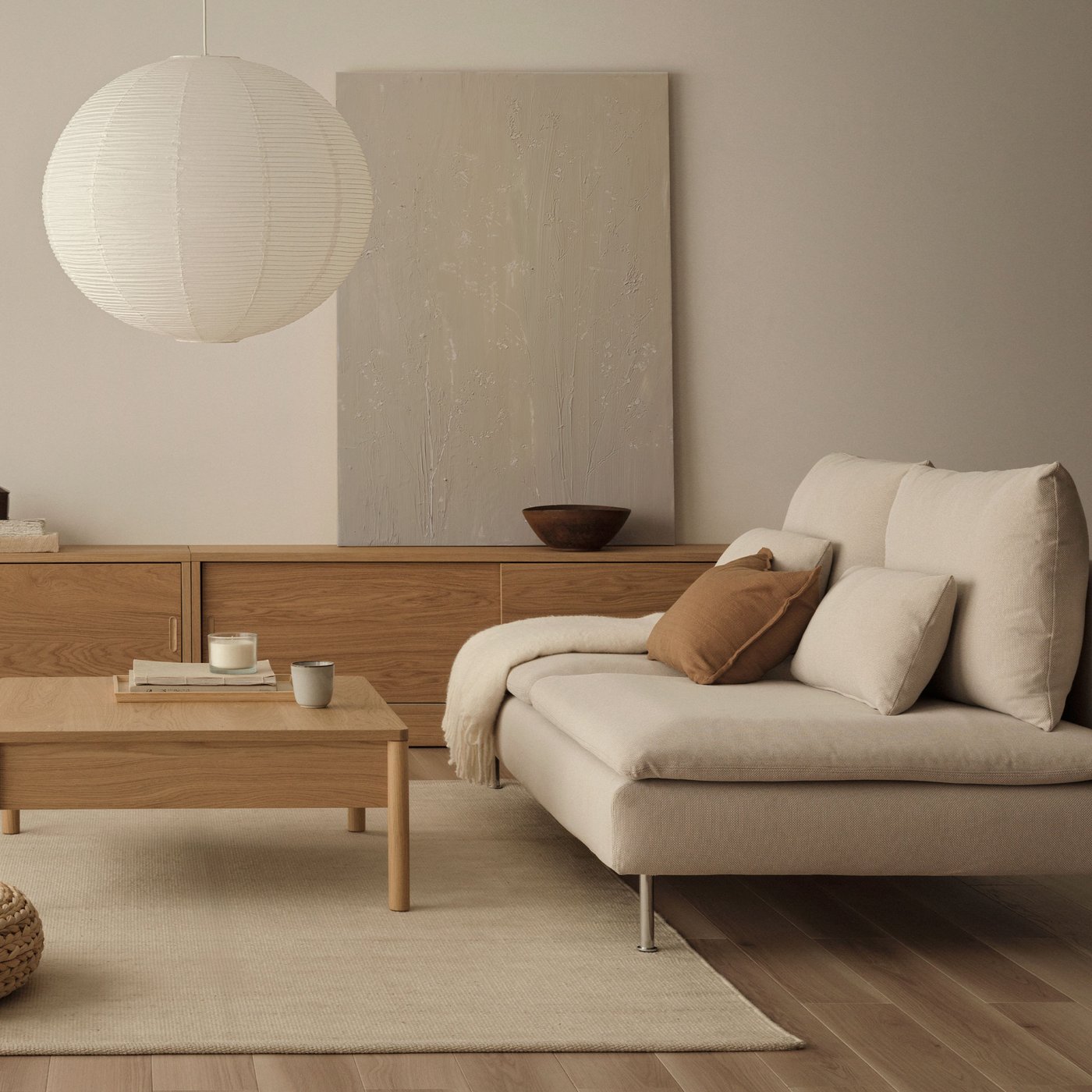 Een Japandi woonkamer met een beige SÖDERHAMN 3-zits modulaire bank, een beige vloerkleed en een houten salontafel met een papieren hanglamp.