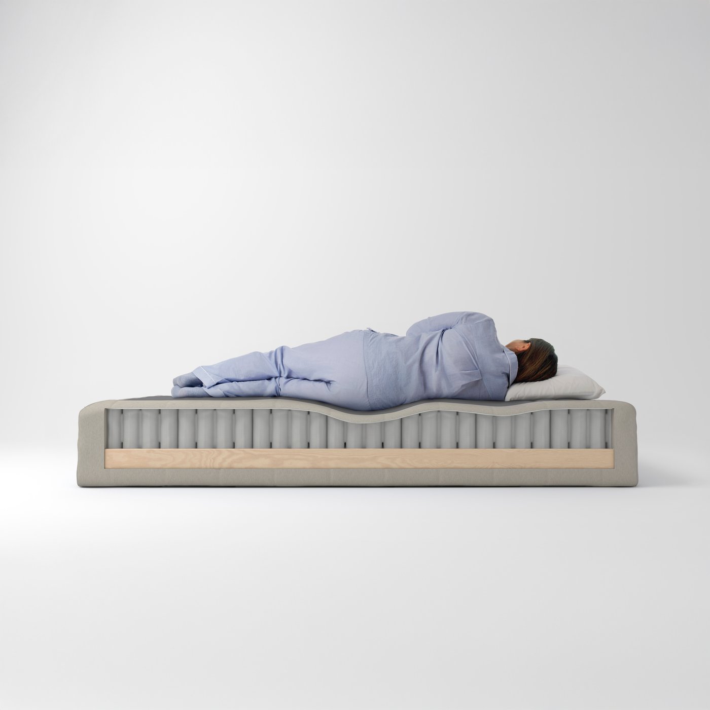 A person lies sleeping on a FEMTÅSEN pocket spring core which has had part of its wooden base cut away on one side.