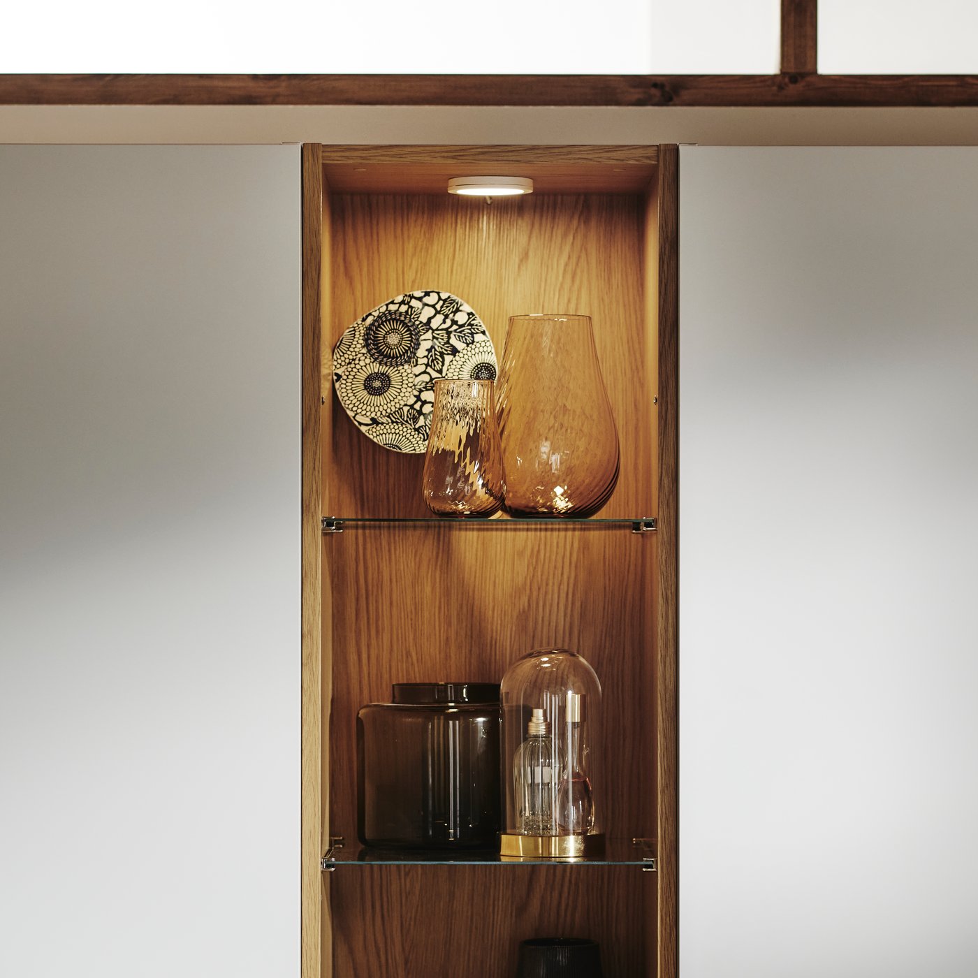 Close-up of PAX mid unit with integrated lighting and different vases and collectibles displayed on the glass shelves.