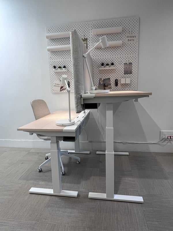 Bureaux assis debouts avec panneau de séparation et panneaux perforés accrochés au mur.