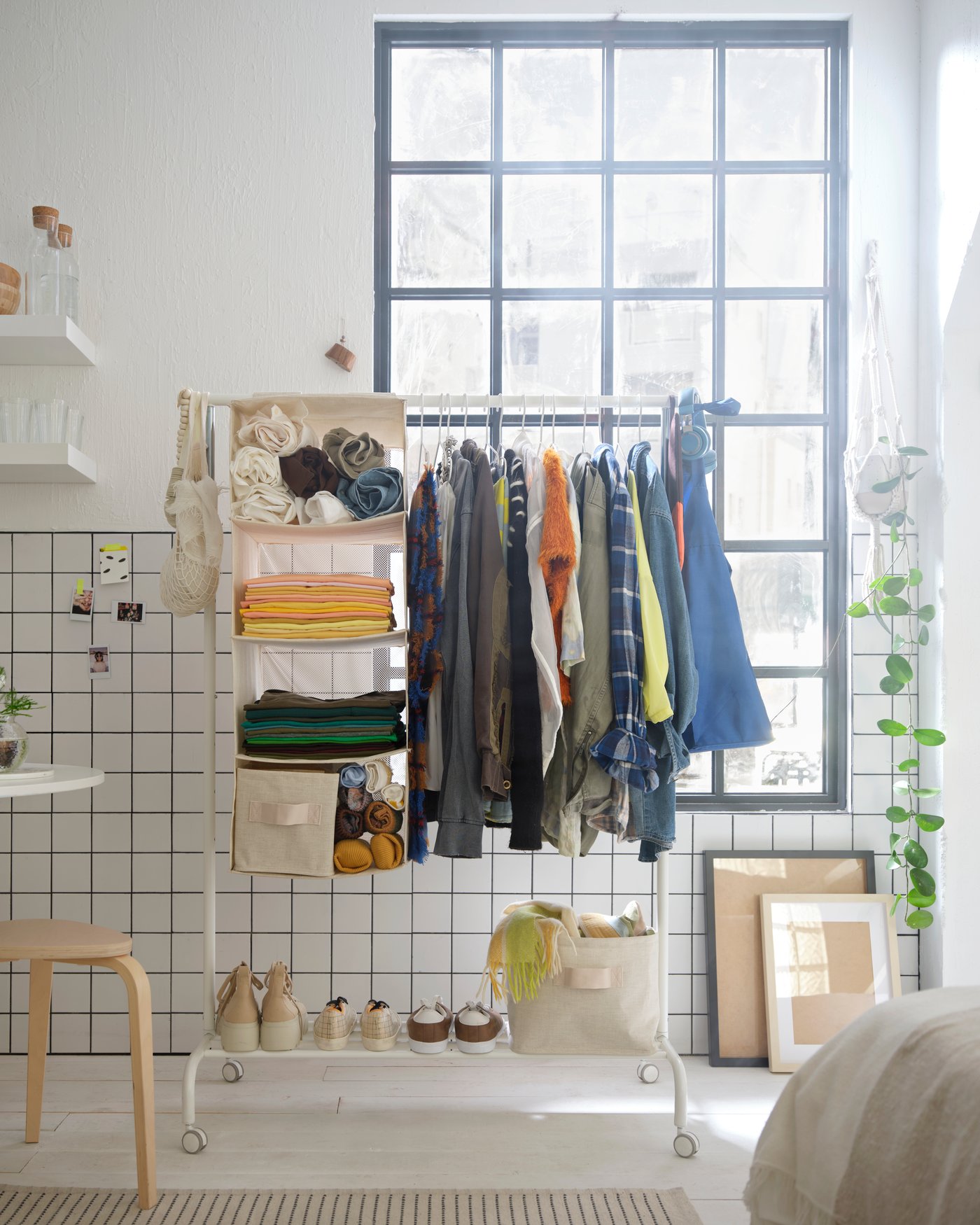 A RIGGA clothes rack with a PURRPINGLA organizer filled with clothes.