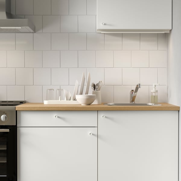 Une armoire inférieure KNOXHULT avec des portes, des tiroirs et un comptoir en bois dans une cuisine moderne au mur carrelé.