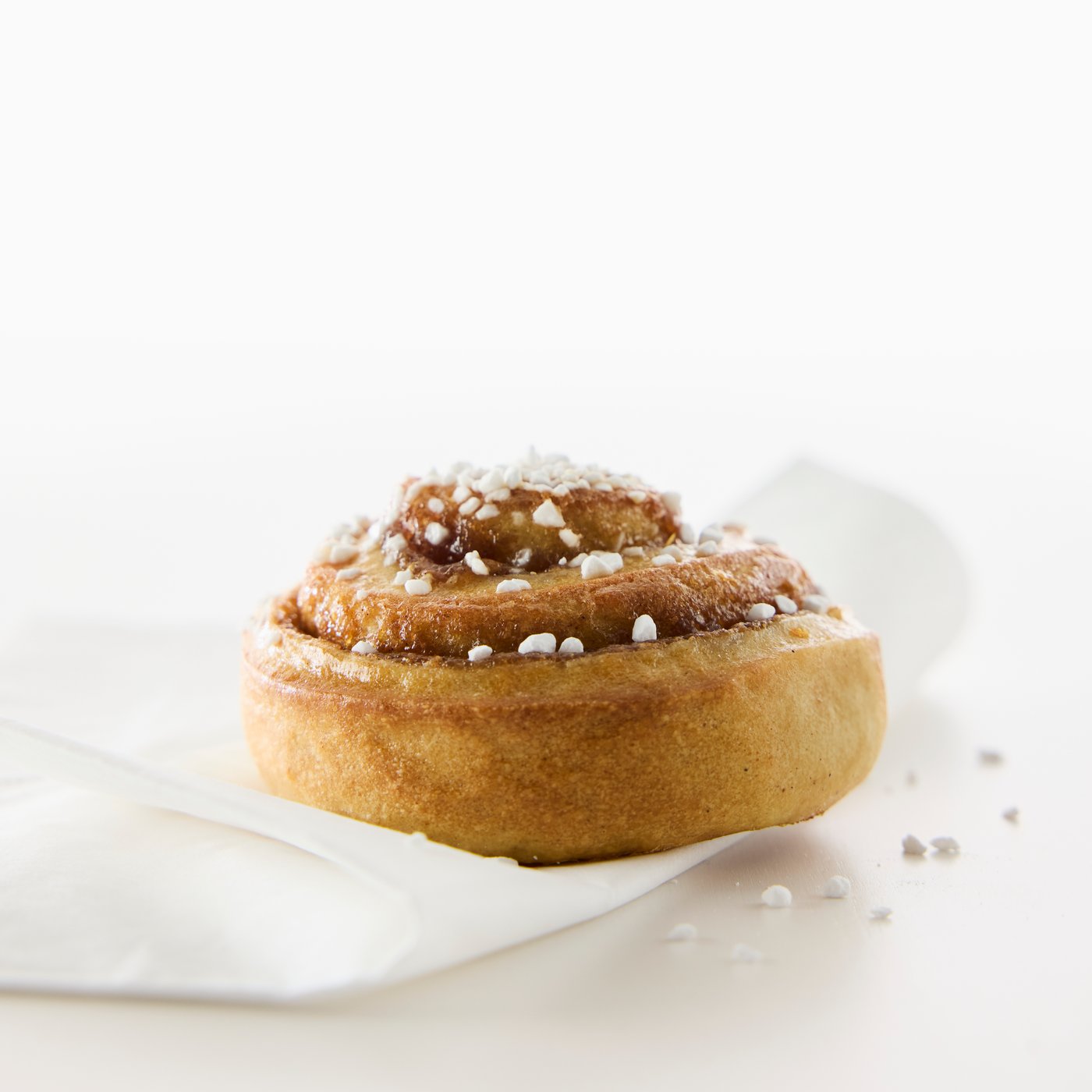 パールシュガーを上に振りかけたおいしそうなシナモンロールのクローズアップ。