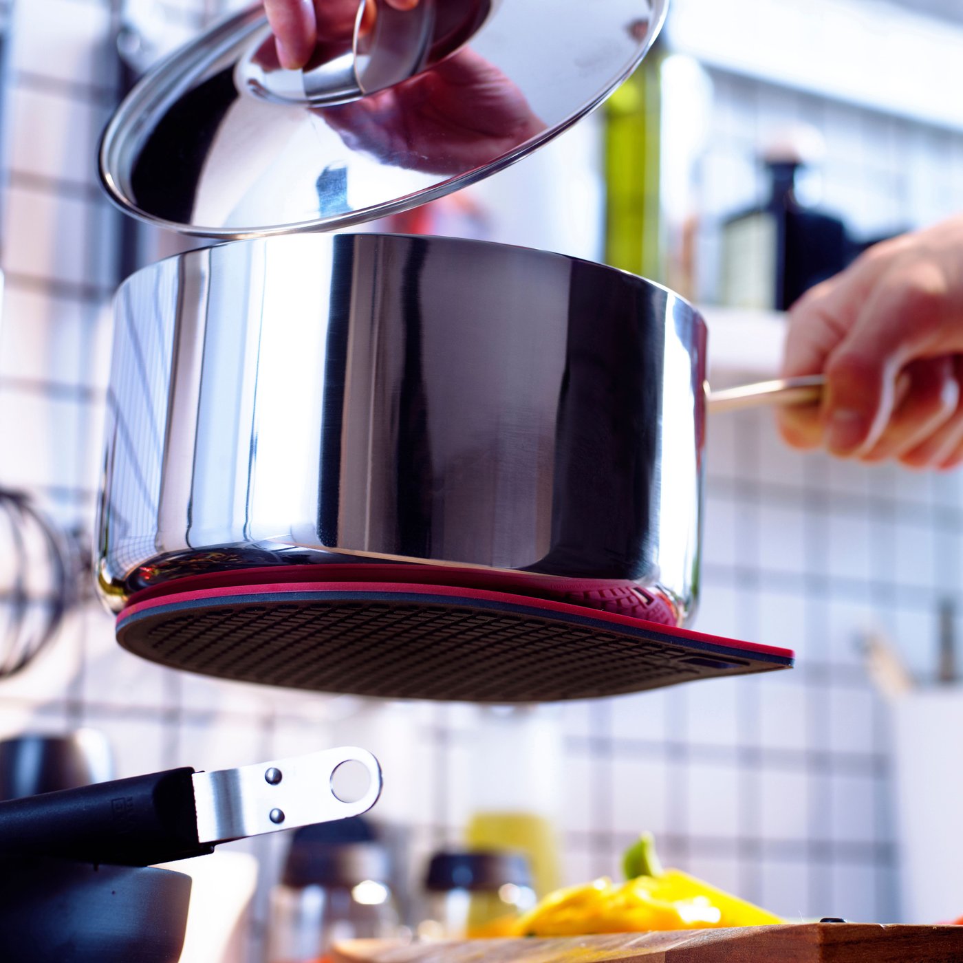 A red/dark grey IKEA 365+ GUNSTIG pot stand, magnetic in the kitchen