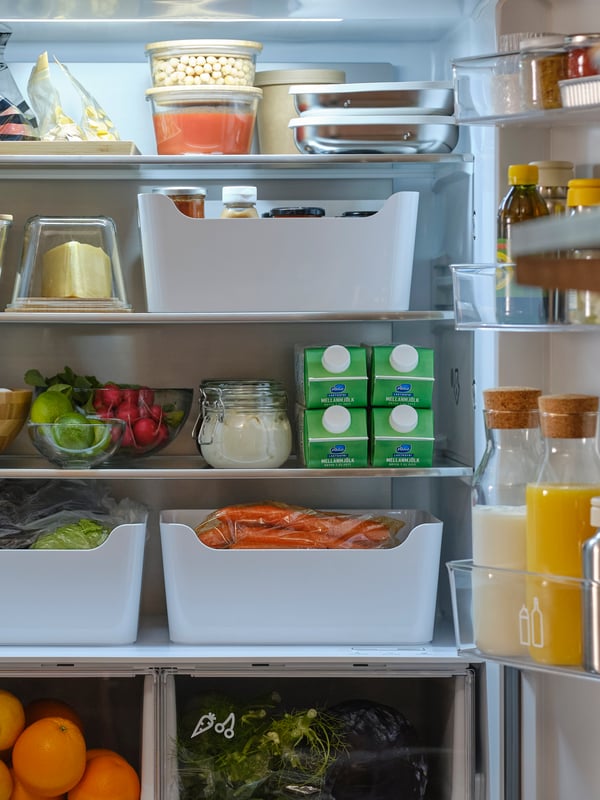 A French door fridge/freezer with both doors open showing foods in containers, boxes, jars, resealable bags and pitchers.