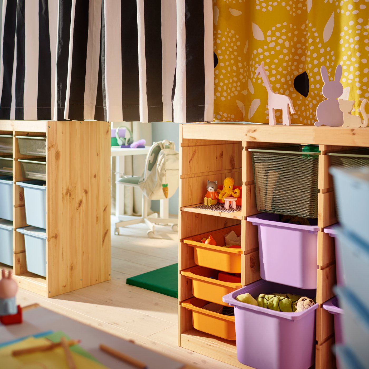 Two TROFAST room dividers in the middle of a shared children’s room with a different curtain pulled across the top of each.