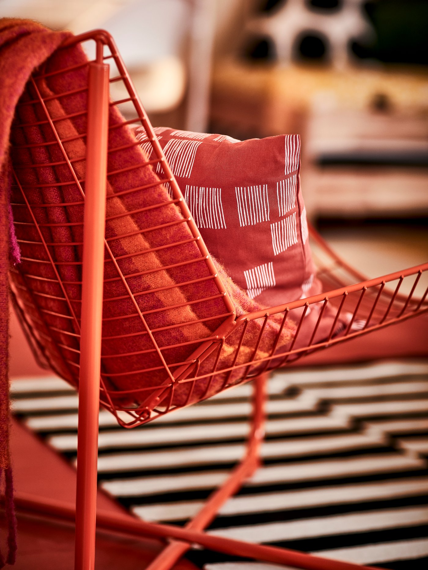 Un fauteuil SKALBODA orange sur lequel un plaid rouge est posé.