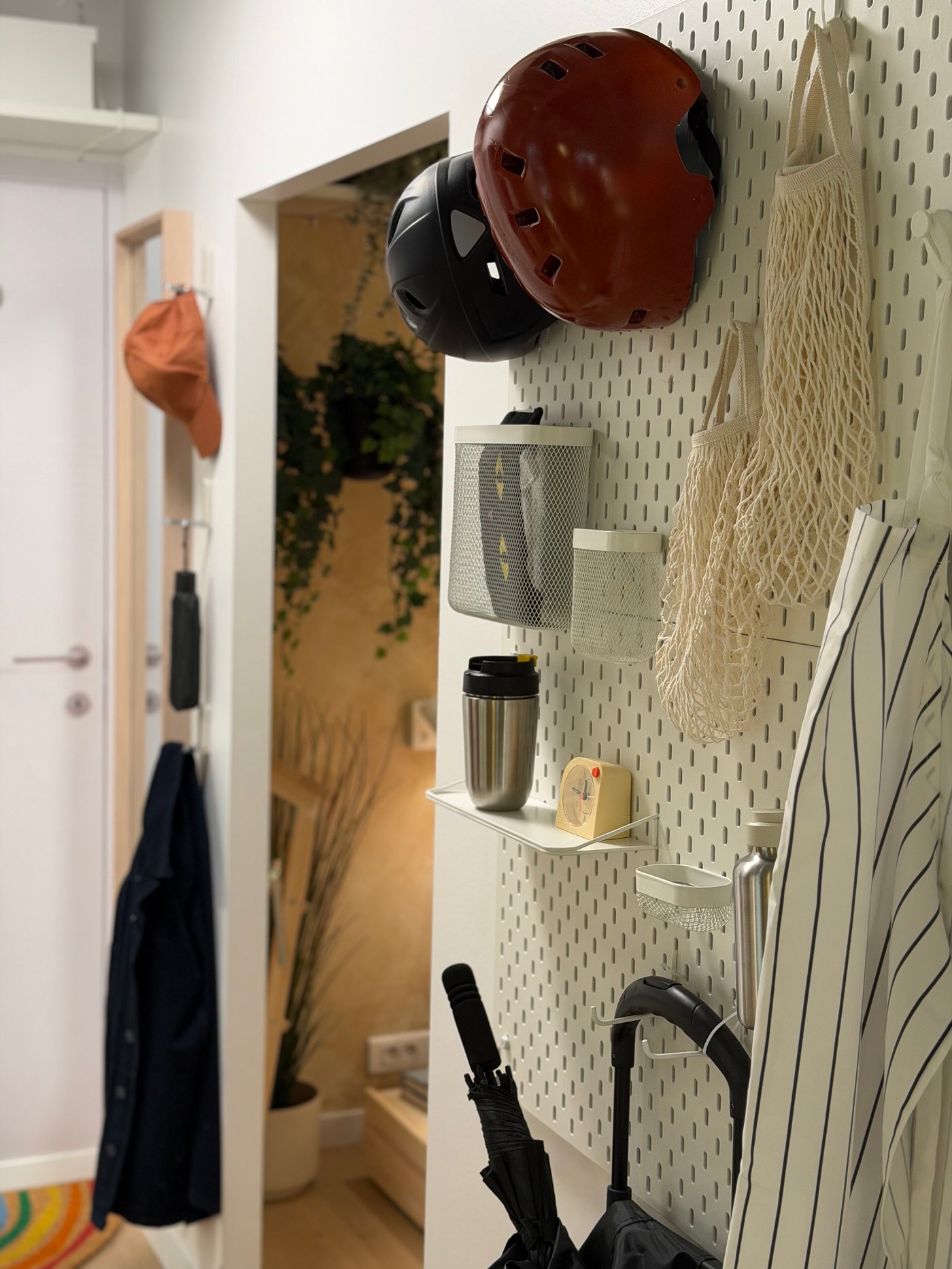 Un coin d'entrée avec des panneaux perforés où sont accrochés casques, et autres accessoires pour sortir