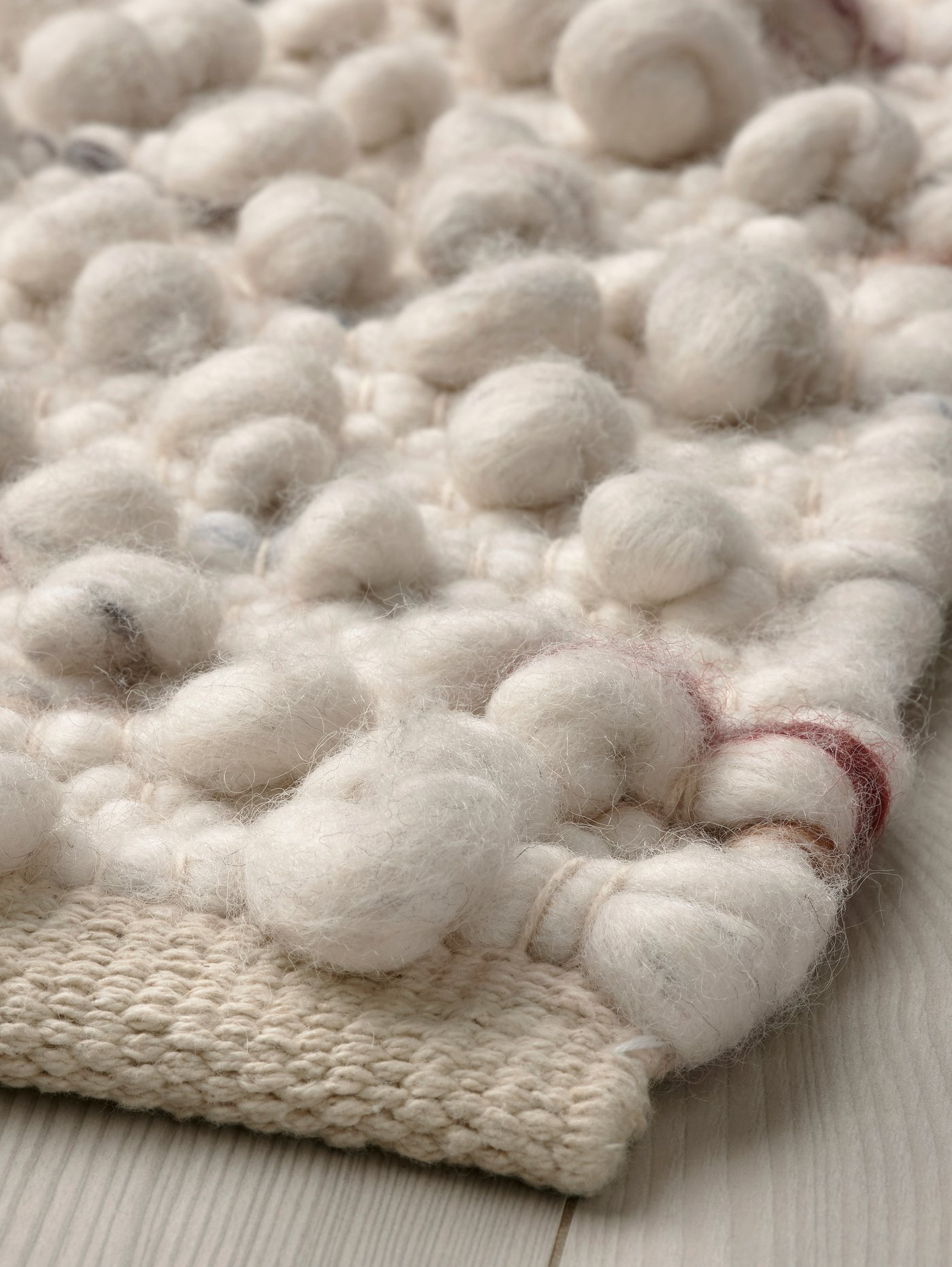 سجادة SVÄRDBORG على أرضية خشبية فاتحة.