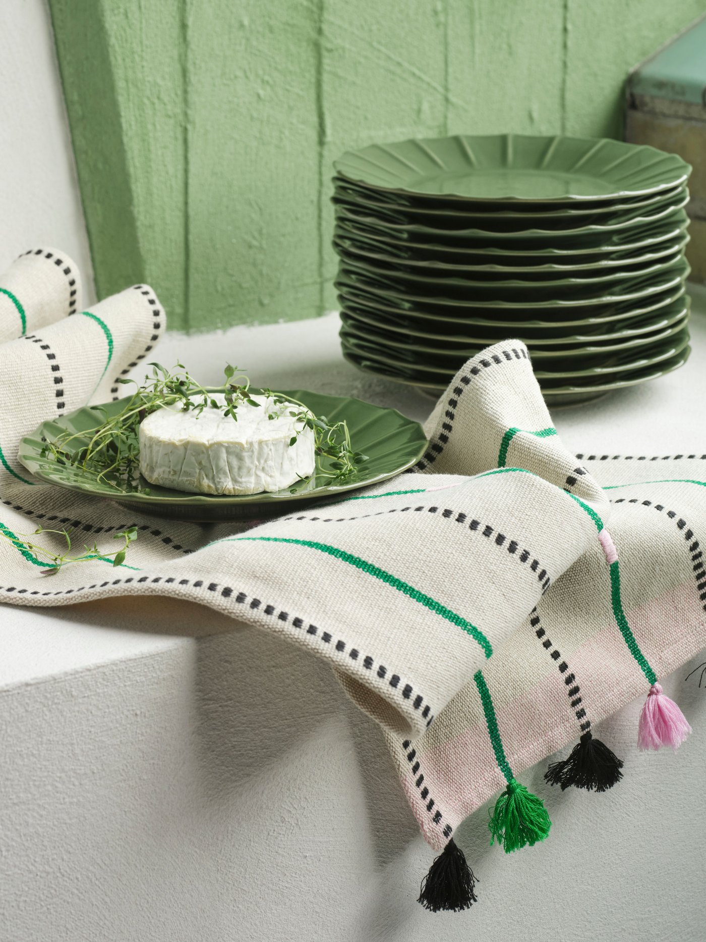 Runner, bianco a righe verdi e piatti verdi della serie MÄVINN su un piano bianco.