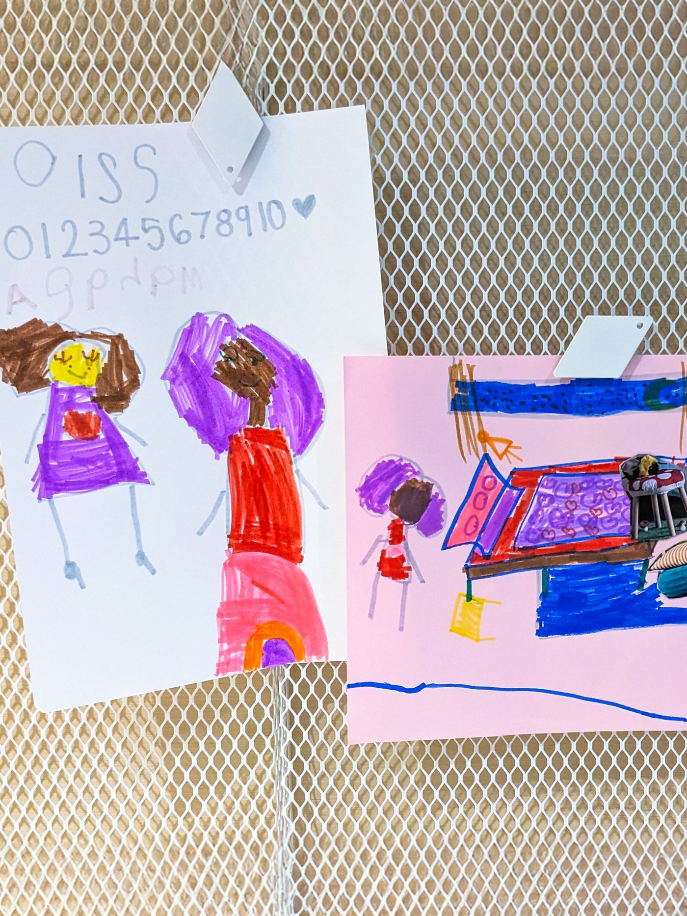 Children's drawing clipped to a peg board