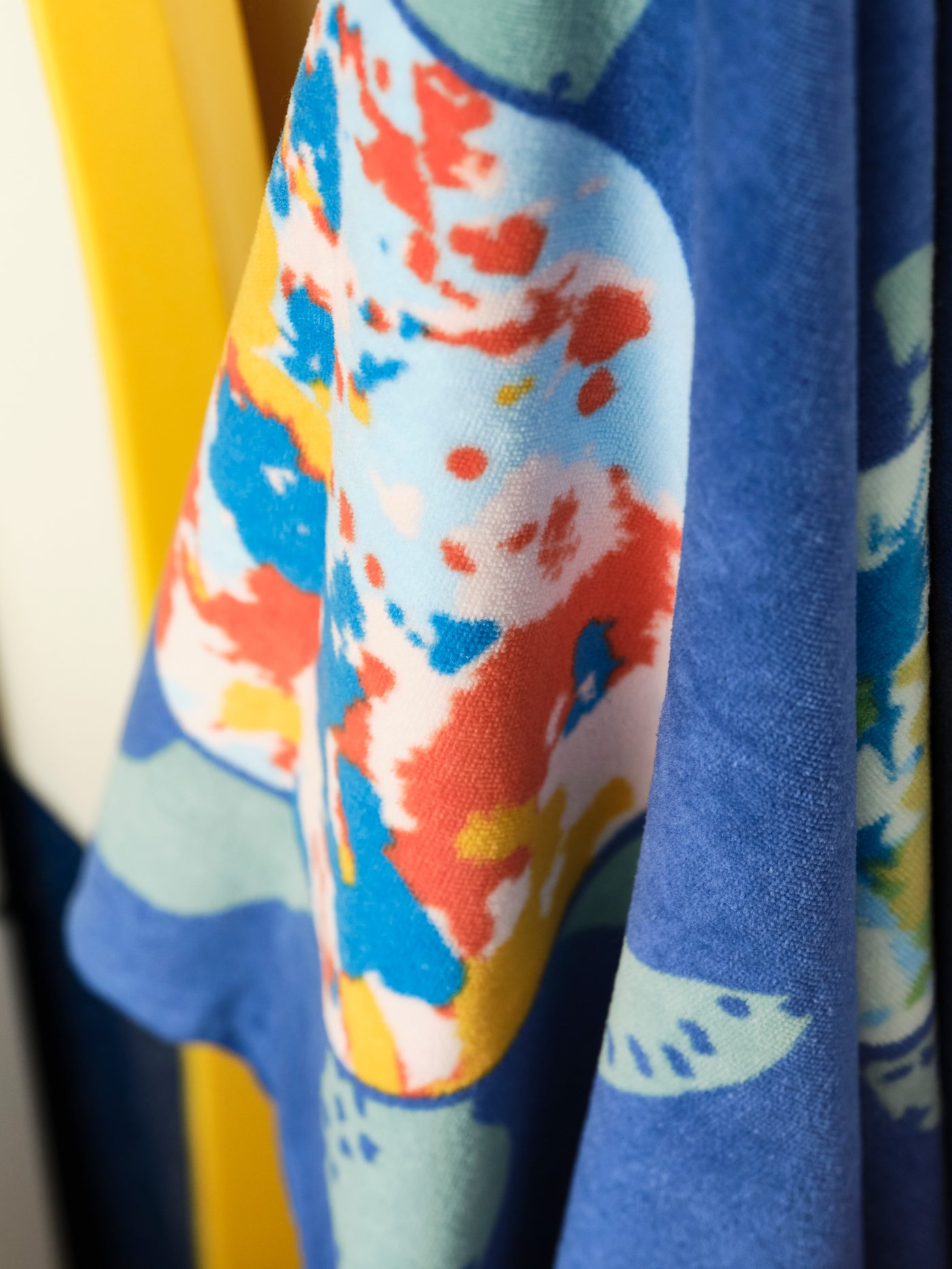 جزء من منشفة حمام BLÅVINGAD بنقش متعدد الألوان يمثل سلحفاة تسبح في المحيط.