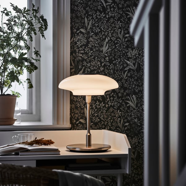 Neonbelyst rum med en vit hylla, hängande plagg och en röd ballong på golvet.