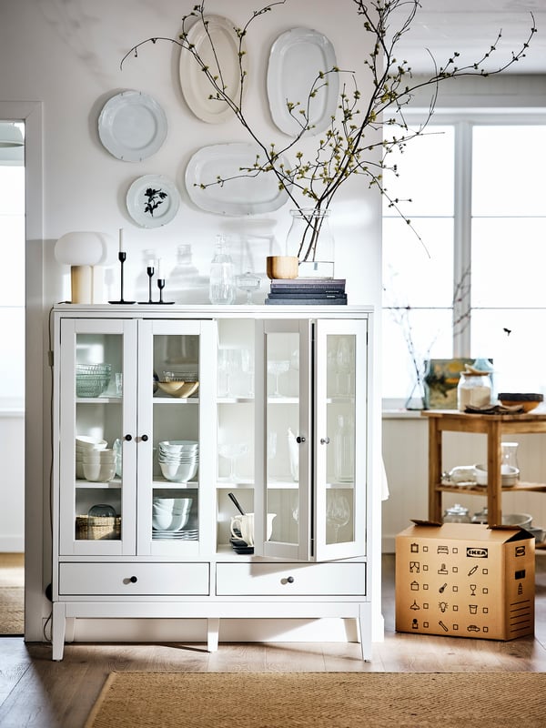 Witte vitrinekast met een lamp, verhuisdoos en een vloerkleed