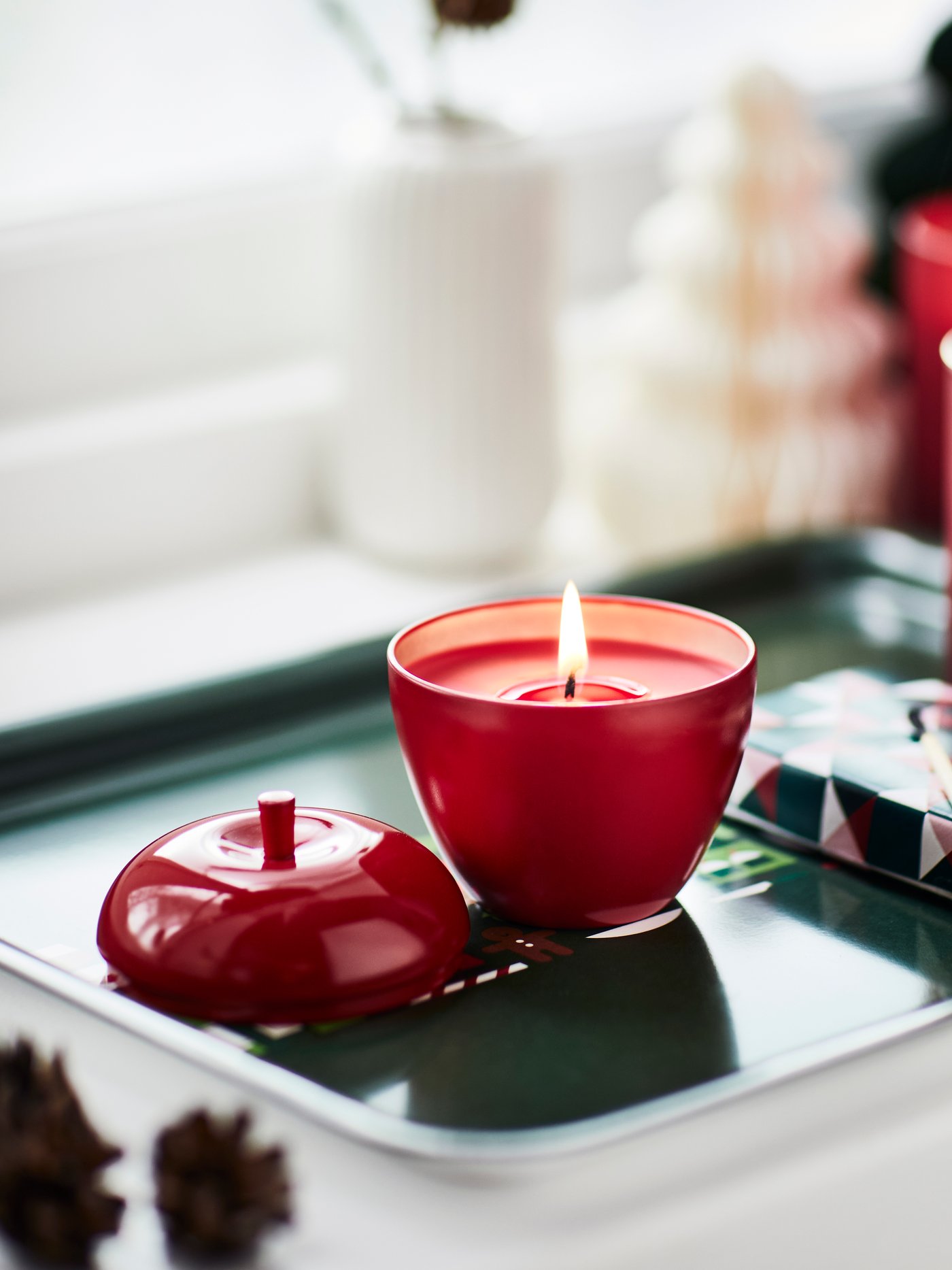 Eine rote VINTERFINT Kerze ist auf einer Fensterbank zu sehen