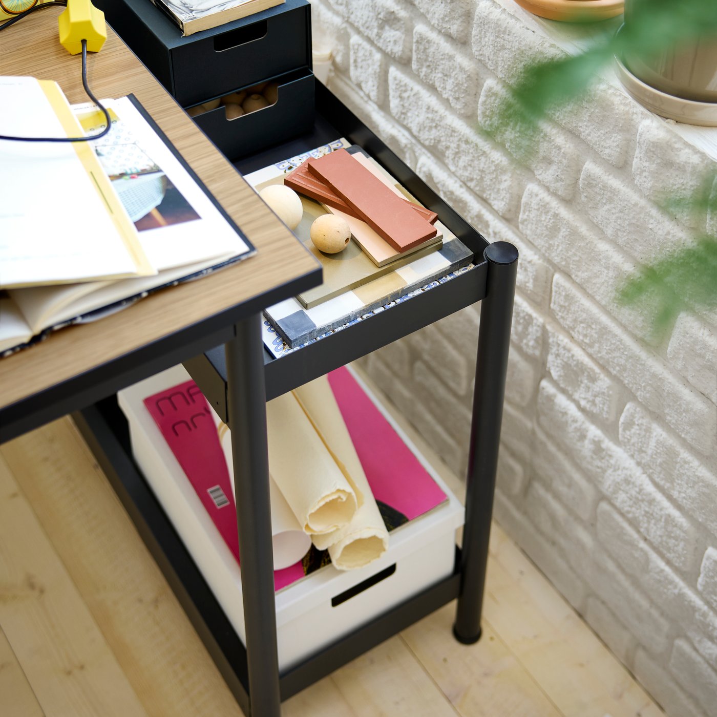 A removable storage unit from a MULLSJÖ desk with colour samples, an anthracite FJÄDERHARV mini chest and a paper box.