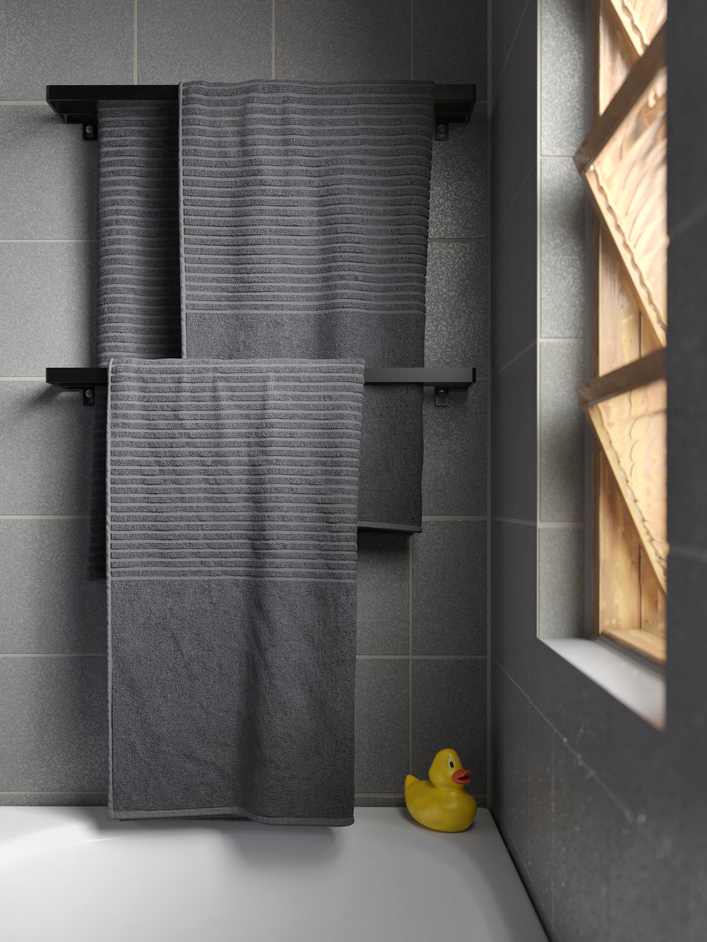 Primer plano de varias toallas de baño de rizo de algodón suave, colocadas sobre dos toalleros negros.