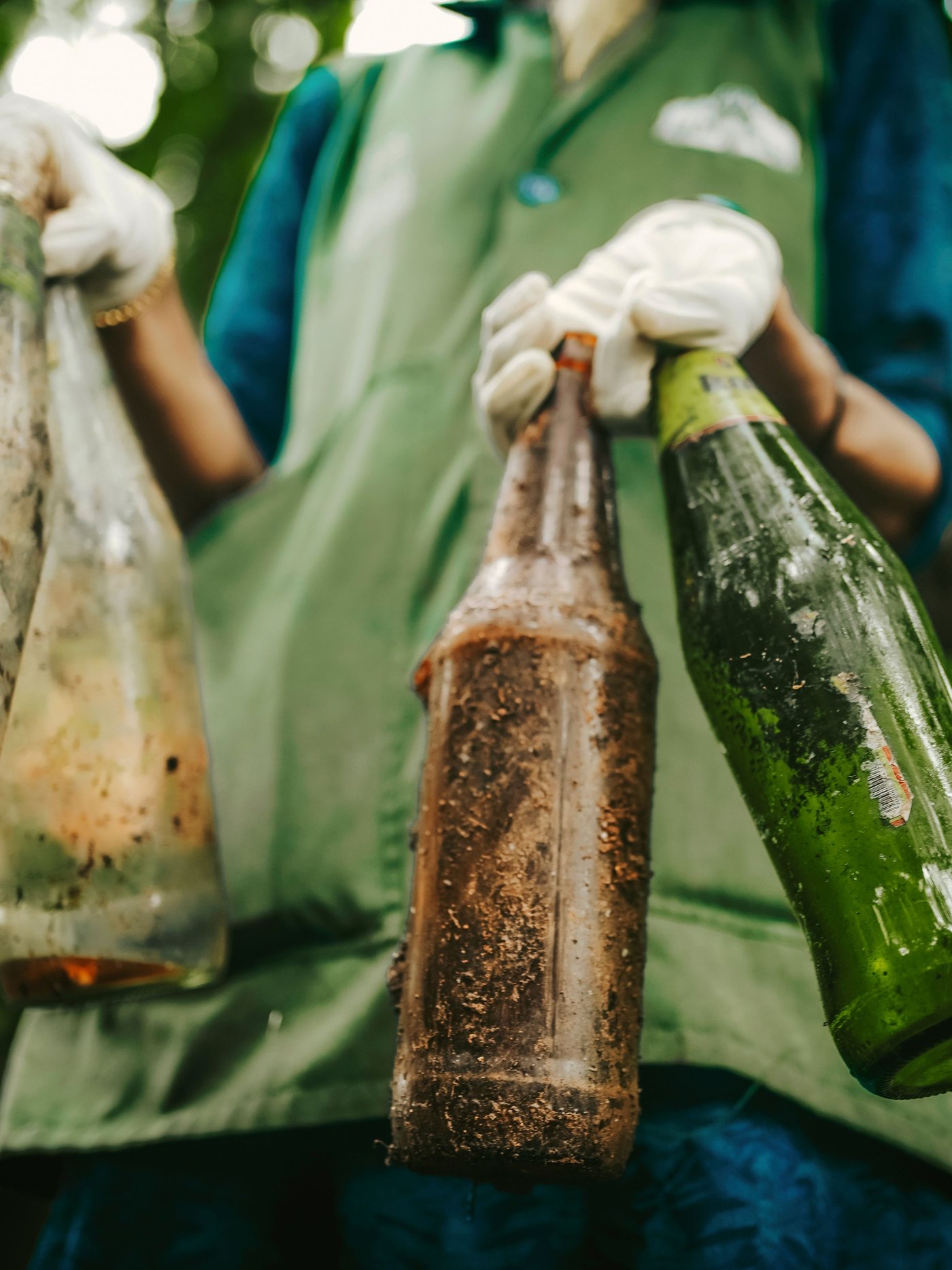 Ein:e Arbeiter:in trägt vier Glasflaschen in den Händen.