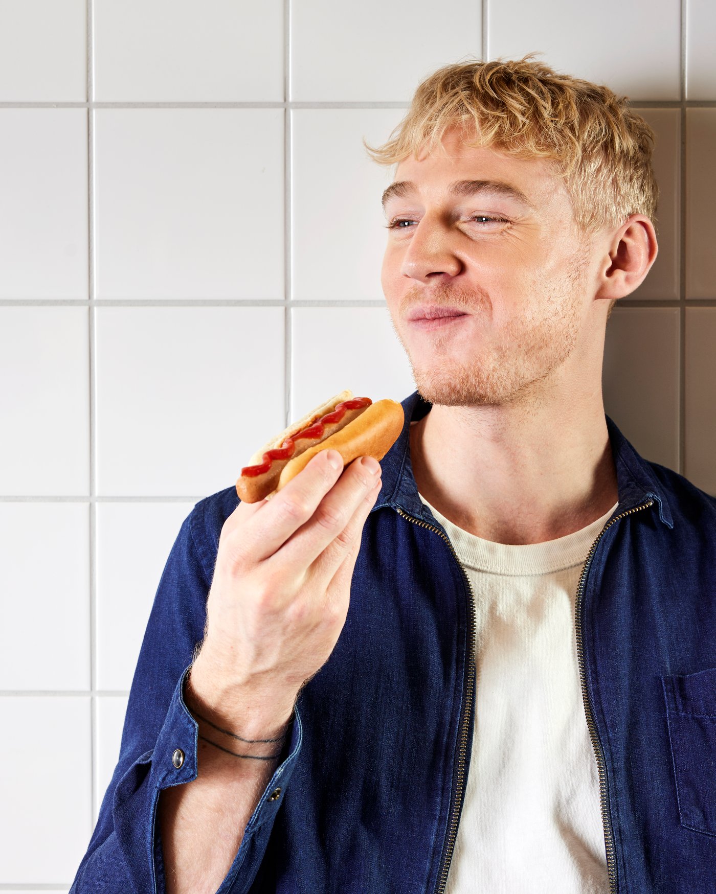 En mand spiser en hotdog og smiler.