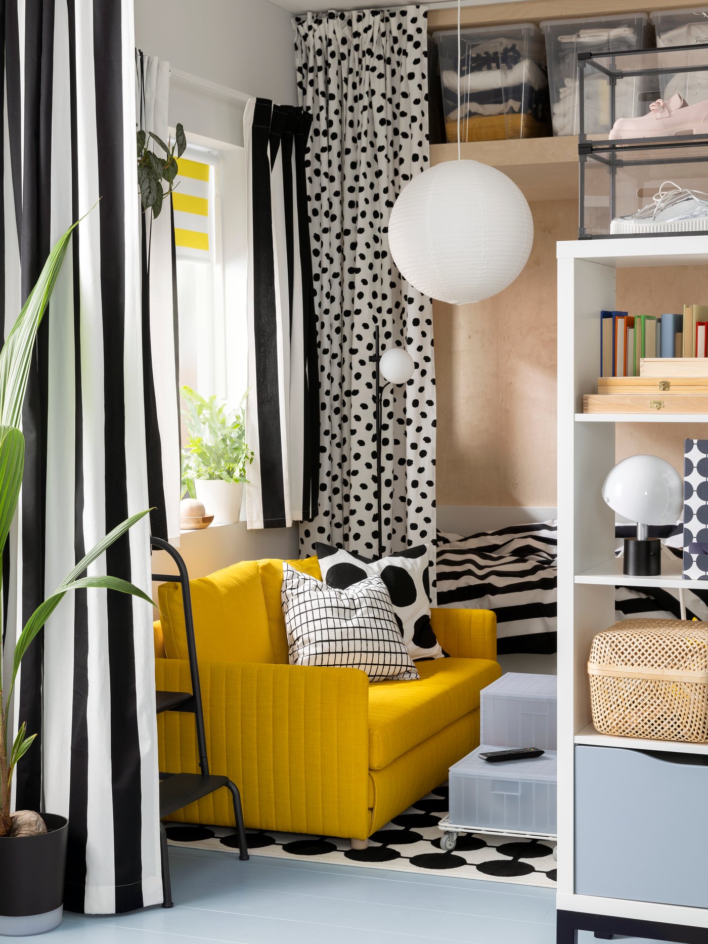 Randiga gardiner hänger från en VIDGA enkelspårsskena framför ett fönster i ett vardagsrum nära en FRIDHULT bäddsoffa.