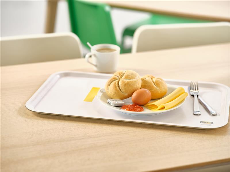 IKEA breakfast consisting of 2 kaiser rolls, 2 slices of cheese, a boiled egg, jam and butter.