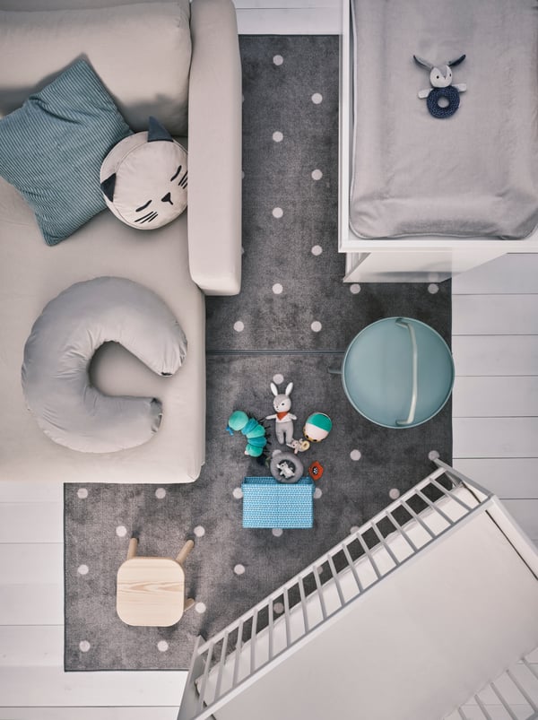 A beige chaise lounge with cushions, a white SMÅGÖRA changing table and cot, plus a FLISAT children’s stool on a grey rug.