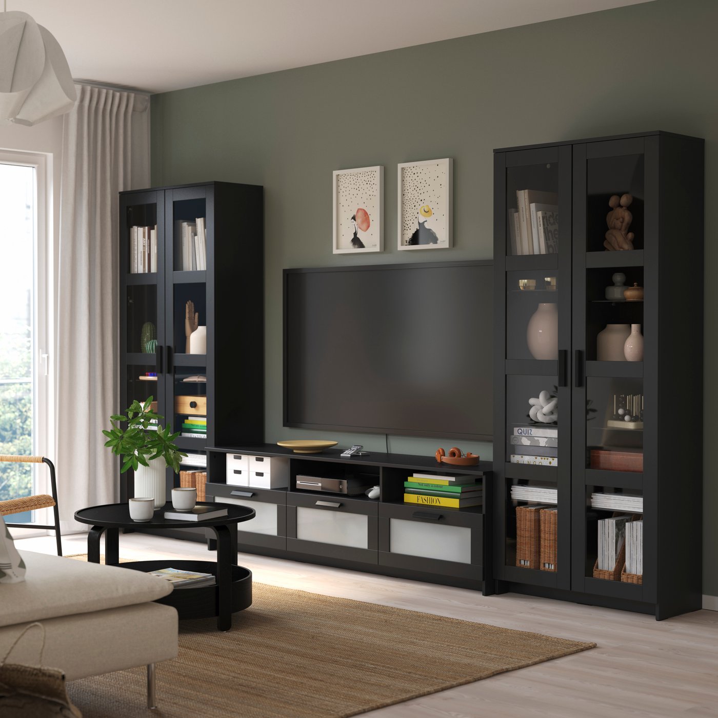 Schwarze BRIMNES TV-Kombination mit Vitrinen und Stauraum rund um einen Fernseher in einem modern eingerichteten Wohnzimmer.