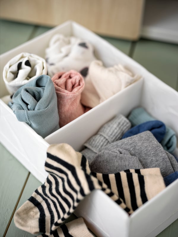 Caja organizadora de ropa color blanco con calcetines en su interior.