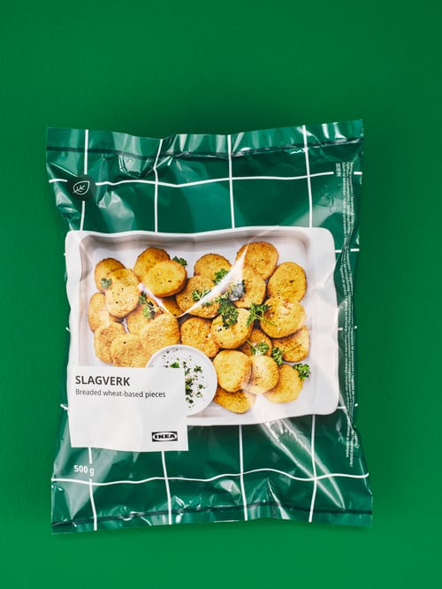 Nahaufnahme einer Packung SLAGVERK panierte Happen auf Weizenbasis auf einer grünen Fläche.