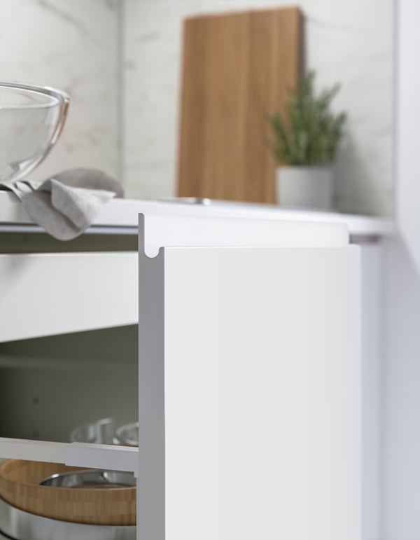 Close up of the open drawers of a modern white high-gloss IKEA VOXTORP kitchen showing the integrated j handles in the drawer front
