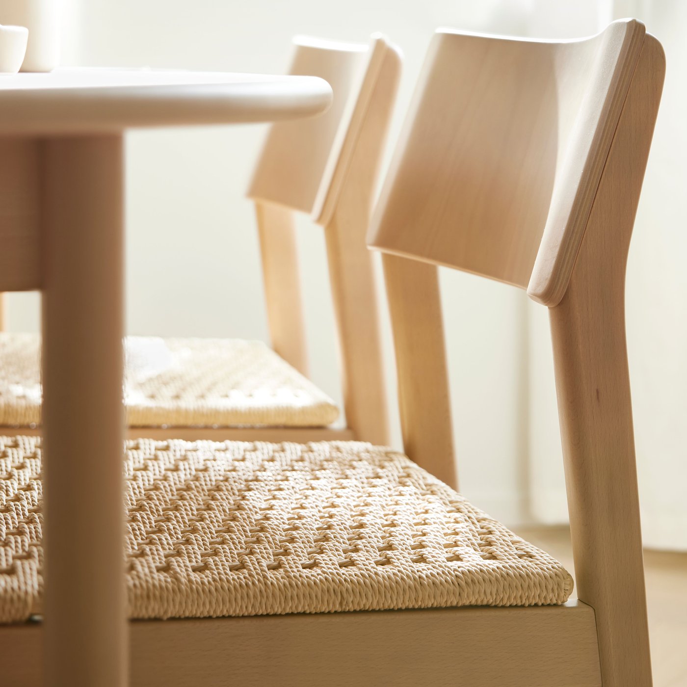 كرسيان SKANSNÄS من خشب زان فاتح أمام طاولة قابلة للتمديد SKANSNÄS مستديرة من قشرة/خشب زان فاتح في غرفة مشمسة.