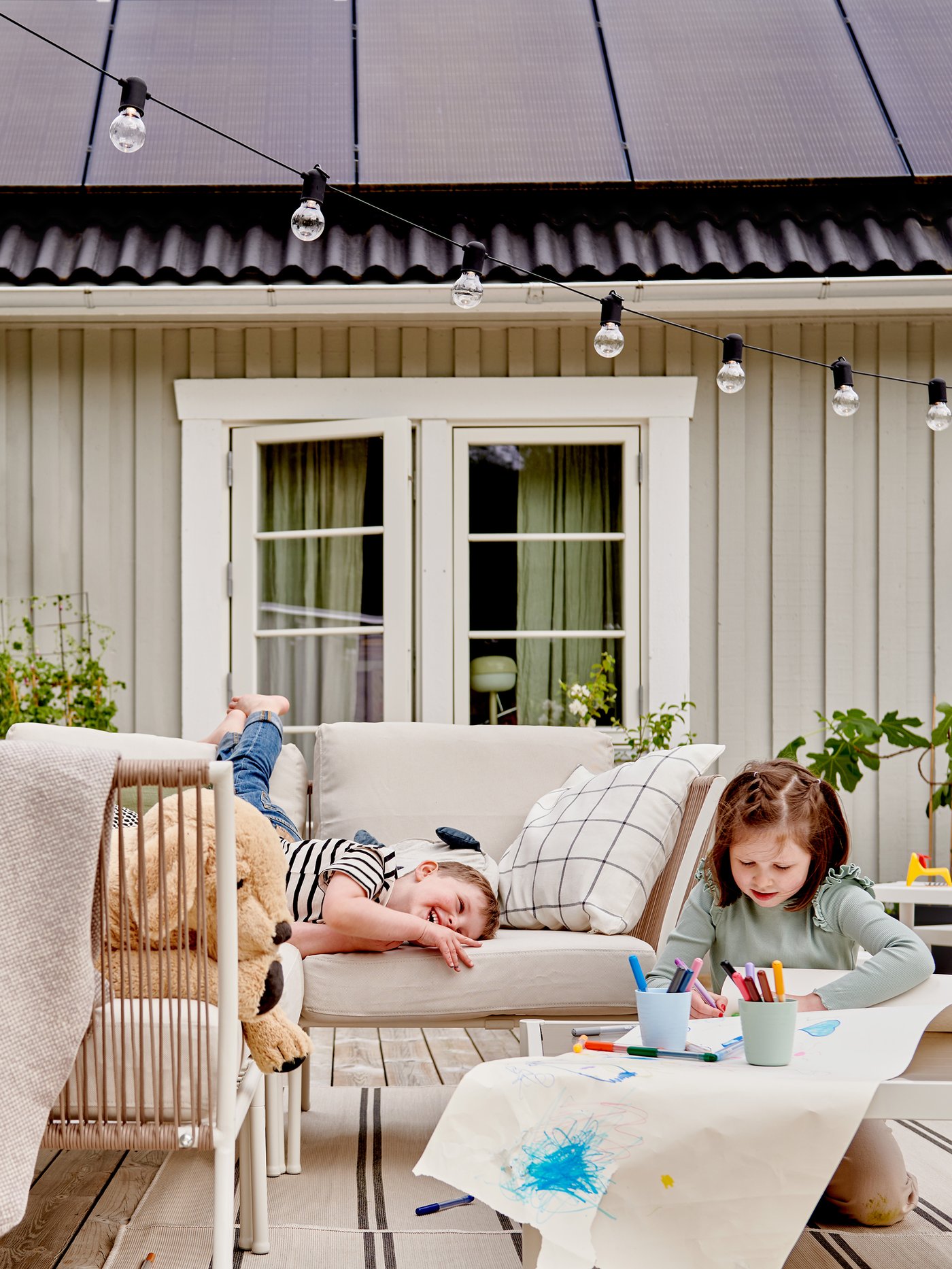 Two kids outside in front of a house with solar panels.