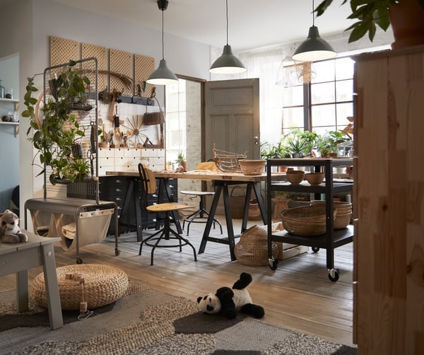 An industrial interior with black tables, black stools, and grey lamps above the dining table.