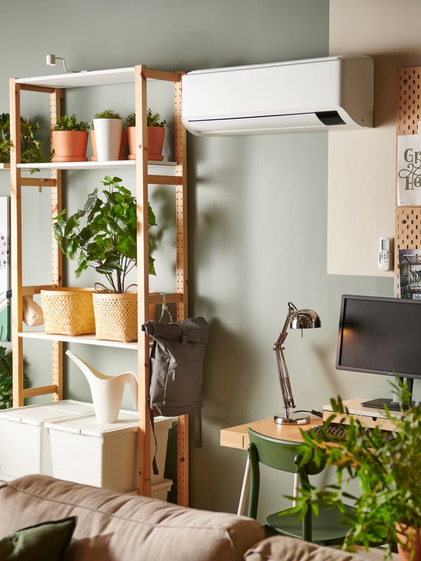 A heatpump in a modern house above a desk and monitor. The space looks modern and has a green wall.