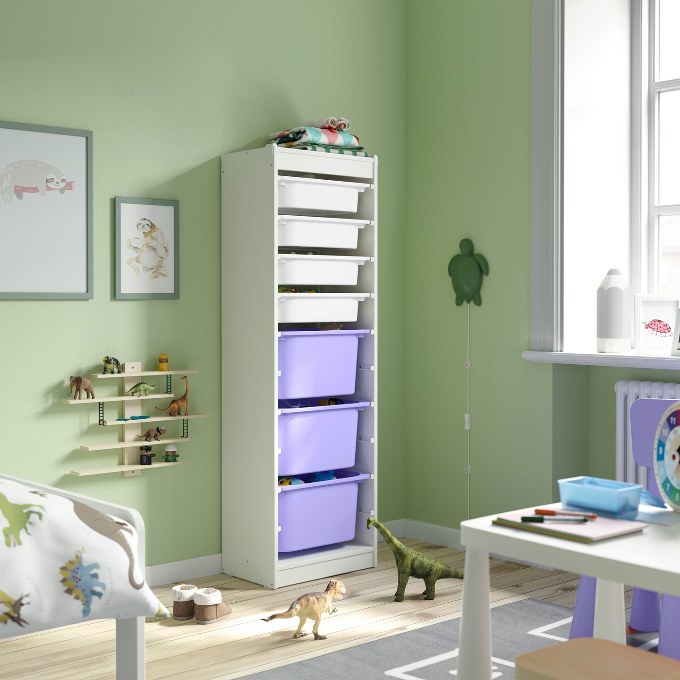 In einem Kinderzimmer ist ein TROFAST Regal mit violetten Boxen zu sehen.