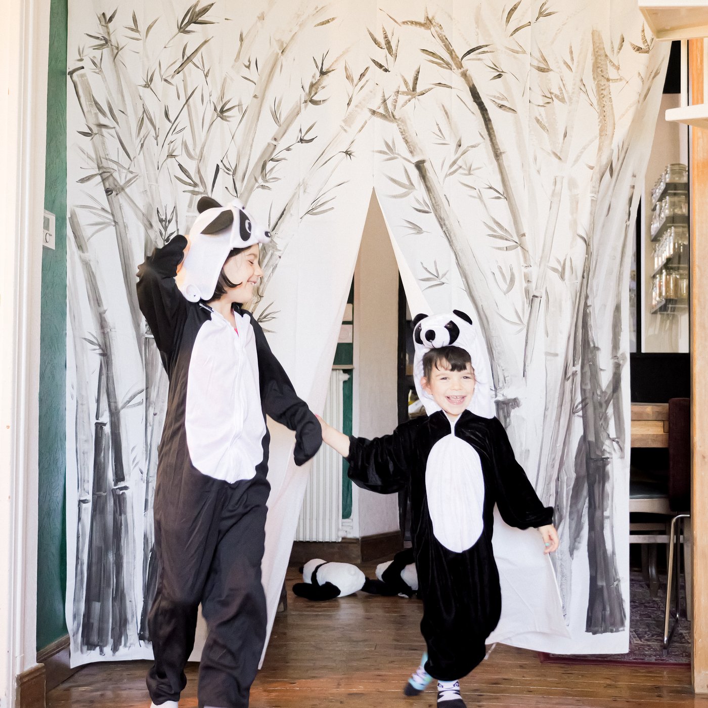 Due bambini con i costumi da panda fanno l'inchino davanti a un sipario di fortuna, creato con una tenda da doccia BJÄRSEN decorata.