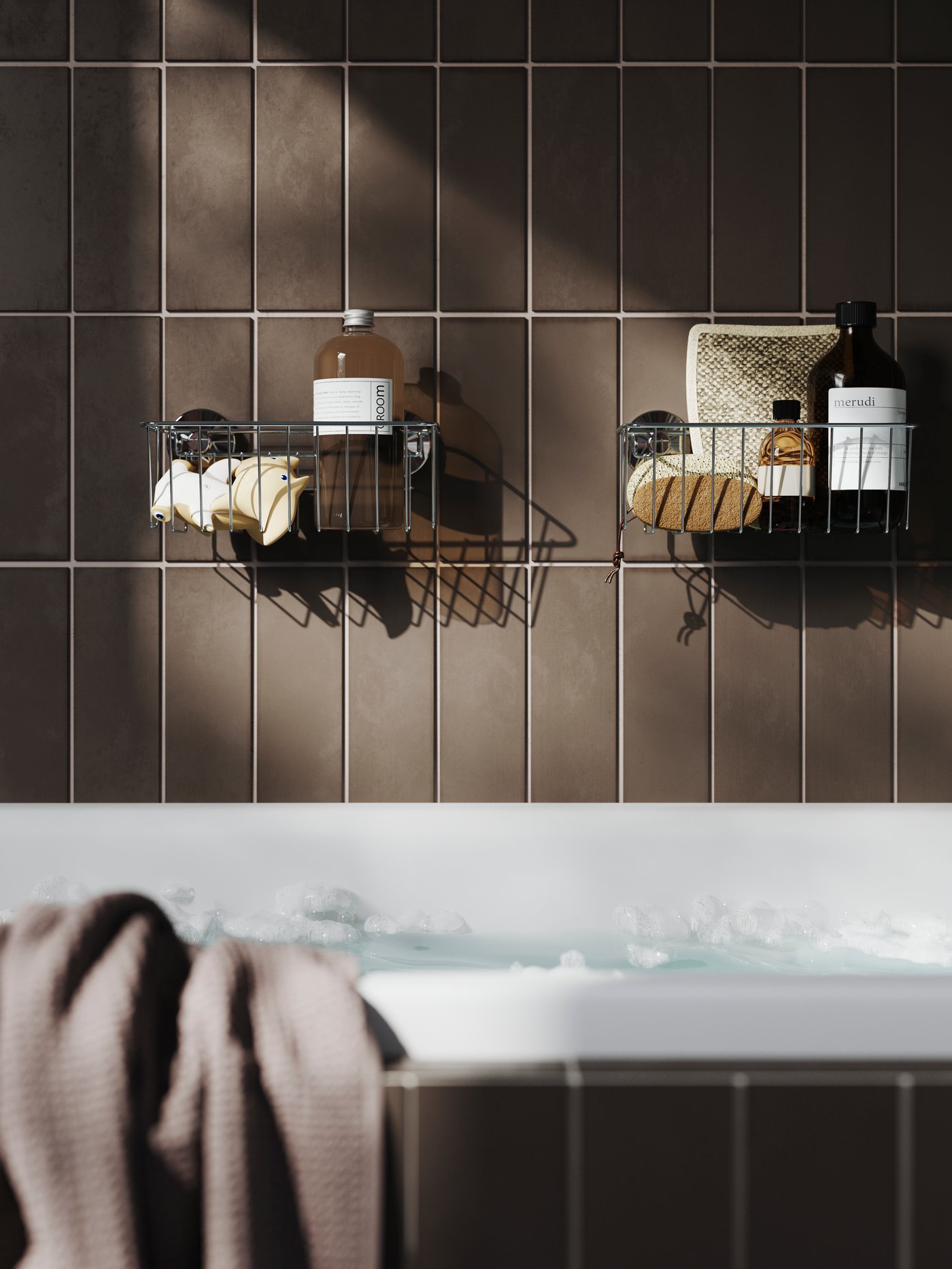 To sorte KROKFJORDEN badeværelseshylder hænger på en brun væg bag et badekar og er fyldt med shampoo og plejeprodukter.