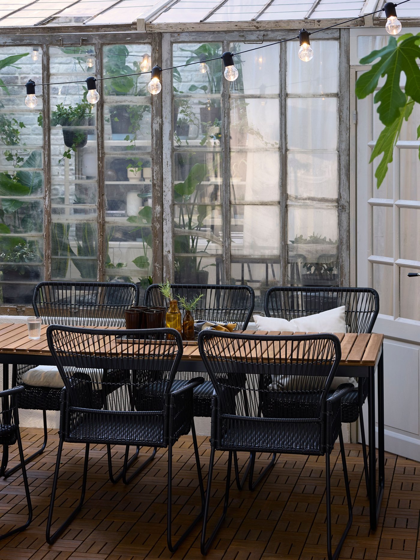 A backyard with a VÄSMAN extendable table and TALLSKÄR outdoor chairs with armrests on an acacia outdoor floor decking.