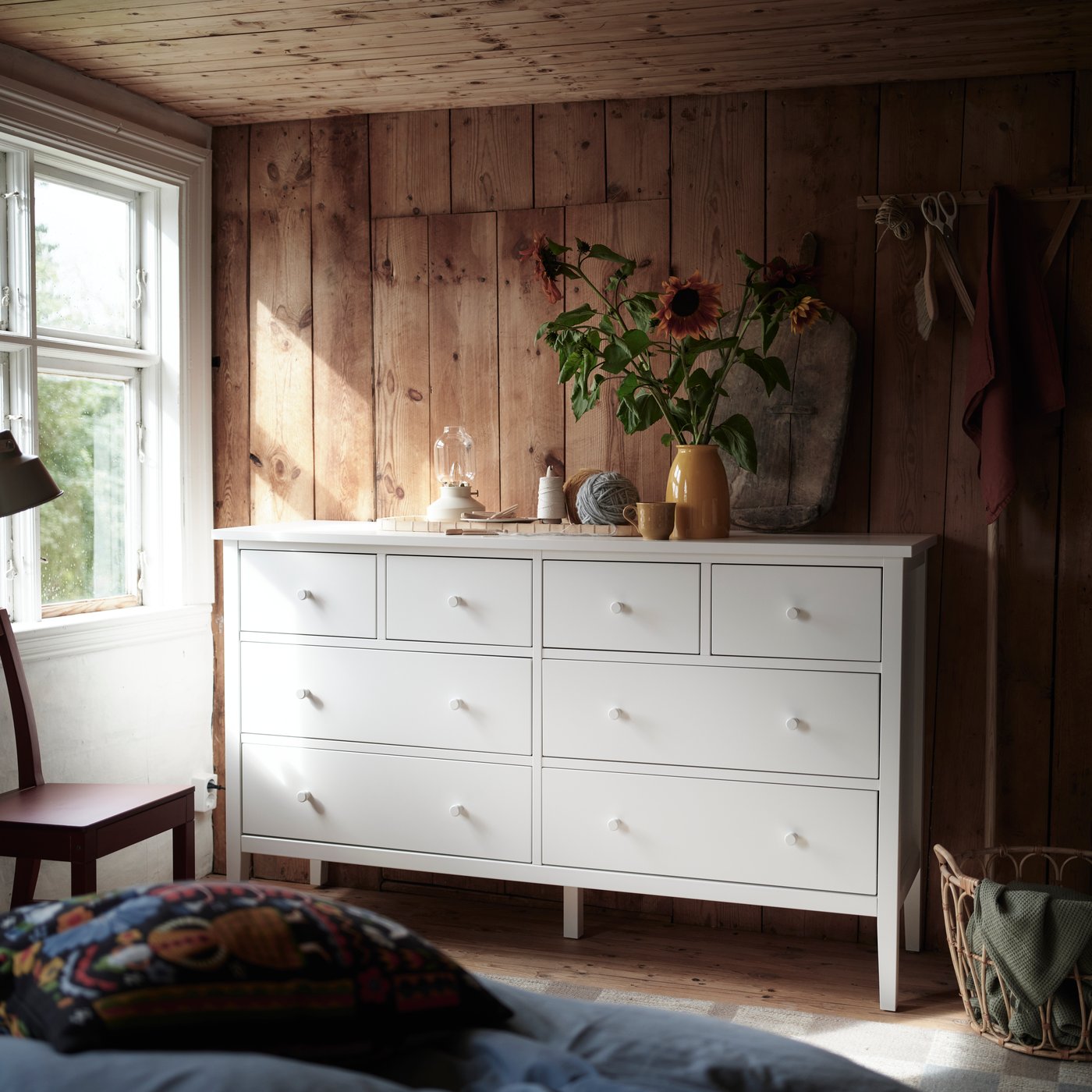 A GULLABERG chest of 8 drawers positioned along a wooden wall with plants and everyday objects displayed on the surface.